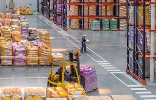 Een magazijnmedewerker coördineert de werkzaamheden in het kader van de logistieke distributie