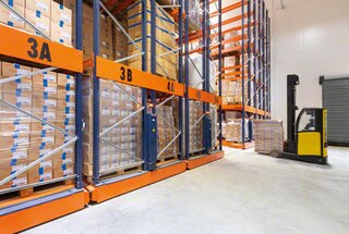 De vorkheftruck kan dan het open gangpad inrijden om een pallet in de stelling op verrijdbare onderstellen te deponeren of eruit te halen